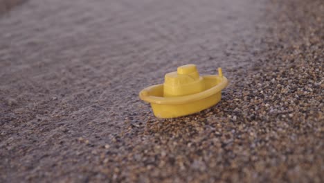 Yellow-toy-boat-on-the-beach-50p