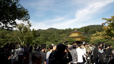 Slow-motion-shot-of-sunlight-falling-on-golden-pavilion-during-daytime-with-many-visitors-at-Kinkaku-ji-in-Kyoto,-Japan