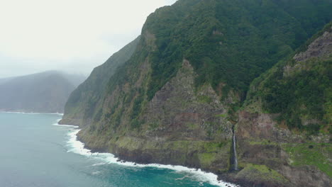 Línea-Costera-Cascada-Miradouro-Do-Véu-Da-Noiva-Madeira-Drone-Shot-Montaña-Con-Olas-Cielo-Panorámico-Océano,-Playa-Naturaleza