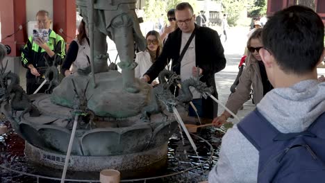 Slow-motion-scene-of-people-at-a-water-purification-fountain-at-Sensoji-Temple,-Japan