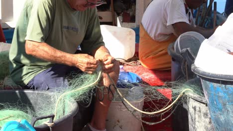 Fisherman-removing-shellfish-from-fishing-net,-Handheld