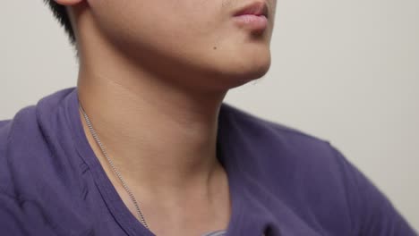 Close-up-shot-of-torso-of-young-Asian-man-dressing,-put-on-blue-cotton-t-shirt