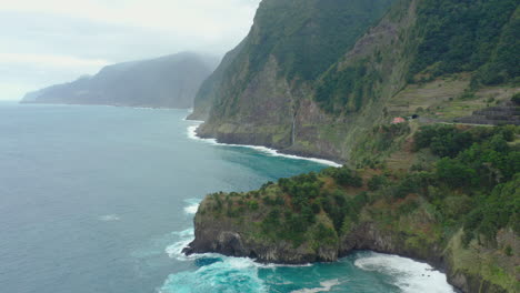 Línea-Costera-Miradouro-Do-Velo-Da-Novia-Cascada-Madeira-Drone-Disparó-Montañas-Nubladas-Con-Olas-Panorama-Cielo-Océano,-Playa