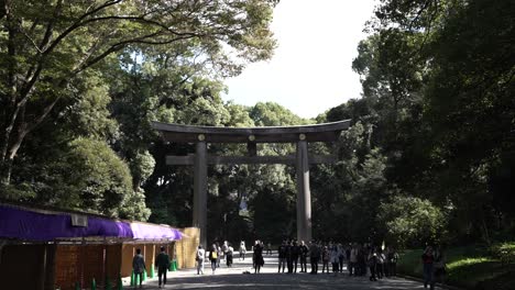 In-a-slow-motion-sequence,-visitors-leisurely-walk-in-proximity-to-Meiji-Jingu-Sanno-Torii-in-Japan