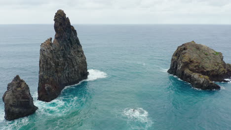 Ribeira-da-Janela-Porto-Moniz-Seixal-Madeira-drone-shot-fly-around-rock-with-sea-ocean-waves-on-a-cloudy-day
