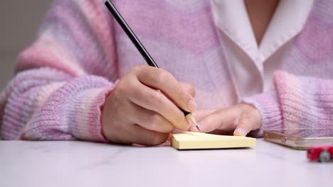 Kreativität-Im-Büro-Nahaufnahme-Der-Hand-Einer-Frau,-Die-Einen-Bleistift-Hält-Und-Ideen-Auf-Gelbem-Papier-Plant
