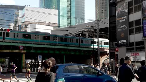 Se-Muestra-Una-Captura-Diurna-De-La-Vía-Elevada-De-La-Línea-Tozai-Del-Metro-De-Tokio-En-La-Estación-Shimbashi-En-Japón,-Con-Vibrantes-Zonas-Peatonales-De-La-Ciudad-Y-Tráfico-De-Automóviles-Visible.