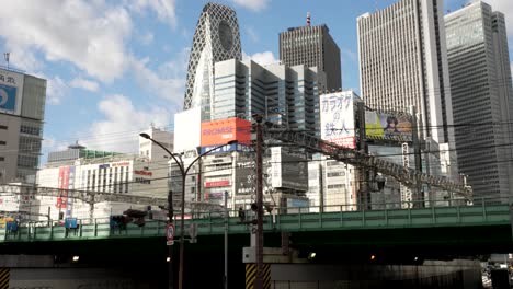 Die-Hochbahnstrecke-Mit-Der-Skyline-Von-Shinjuku-Im-Hintergrund-Symbolisiert-Die-Dynamische-Synergie-Von-Effizientem-Transport-Und-Großstädtischer-Architektur-In-Shinjuku,-Tokio,-Japan