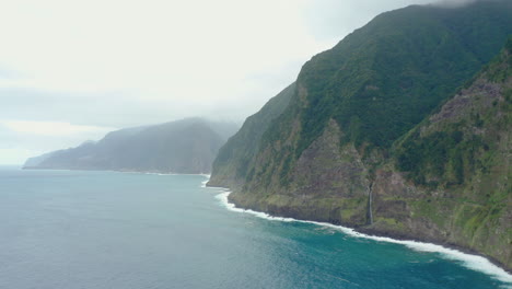 Línea-Costera-Miradouro-Do-Velo-Da-Novia-Cascada-Madeira-Drone-Disparó-Montaña-Con-Olas-Panorama-Cielo-Océano,-Playa