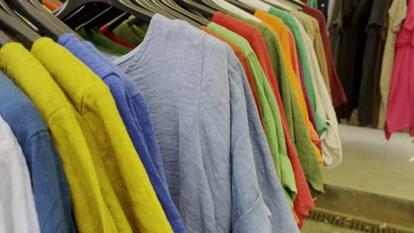 Bunte-Dünne-Hemden-Und-Kleider-Auf-Kleiderbügeln-Zum-Verkauf-Auf-Einem-Markt-Im-Sonnenschein-In-Frankreich