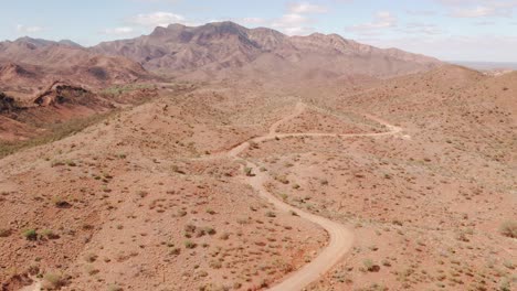 Aerial-of-Flinders-Ranges-mountains-and-winding-dirt-road,-South-Australia
