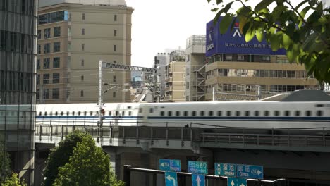 Capturando-La-Escena-Diurna-De-Una-Vía-De-Tren-Elevada-En-El-Barrio-De-Minato,-Tokio,-Japón,-Con-Un-Tren-Bala-De-La-Línea-Principal-De-Tokaido-Que-Pasa.
