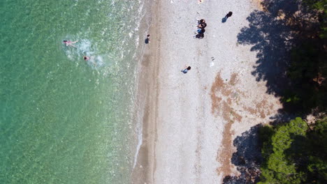 A-drone-descends-straight-down-for-a-shot-of-a-family-enjoying-a-day-at-the-beach