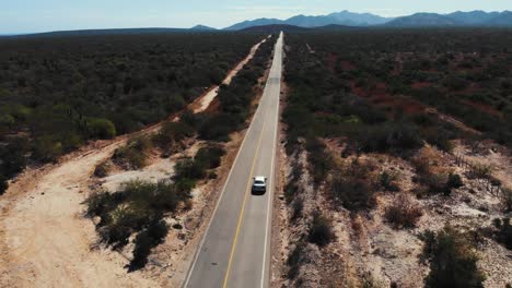 Aerial-view-of-vehicle-on-remote-highway-in-Mexico,-a-straight-road-through-Mexican-desert