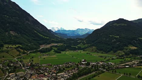 Panoramic-drone-shot-of-a-small-village-surrounded-by-the-Swiss-Alps,-Brienzer-Rothorn-mountain-in-Emmental-Alps,-Switzerland,-Europe
