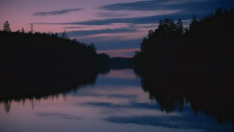 Magical-sunset-reflection-in-Swedish-lake-with-dark-forest-silhouette