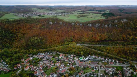 Aerial-view-of-Lichtenstein,-Germany-in-the-fall,-overlooking-a-village-surrounded-by-autumn-colored-trees
