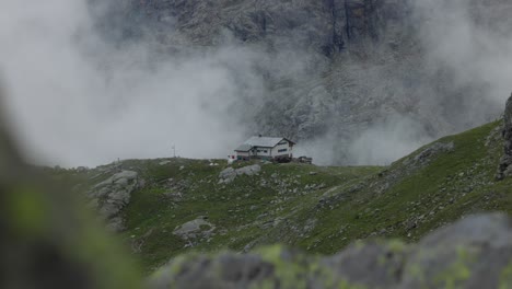 Building-Seen-In-Background-In-Valmalenco-Mountains-With-Rising-Foggy-Clouds