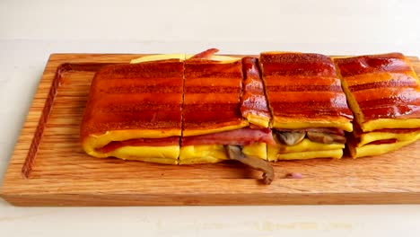 Delicious-Portuguese-sandwich-on-wooden-board-cut-into-pieces-for-eating,-close-up
