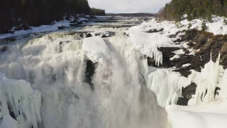 Drone-footage-of-Swedens-largest-waterfall,-Tännforsen-during-spring-and-flood,-zooming-out-from-the-objective