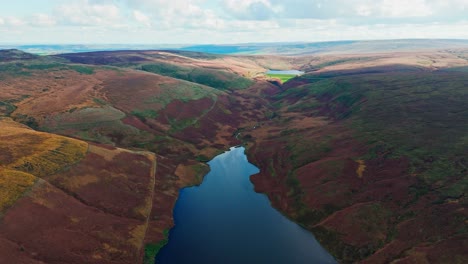 Aerial-drone-video-of-the-beautiful-English-countryside,-Wild-landscape-showing-moorlands-covered-in-heather,-large-lakes-and-blue-water