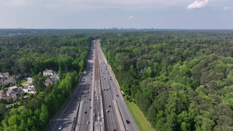 Cinematic-drone-shot-of-Atlanta-city-interstate-highway-traffic,-Georgia-state-route-driving-through-park,-USA
