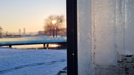Glass-cabin-and-frozen-lake-at-sunrise-on-a-cold-winter-morning
