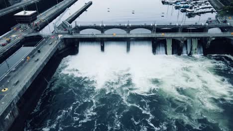 Stationary-aerial-view-of-water-cascading-down-the-Ballard-Locks-on-an-overcast-day-in-Seattle,-WA