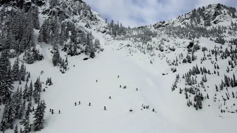 Retreating-aerial-shot-of-snowy-backcountry-skiers-in-Snoqualmie,-WA