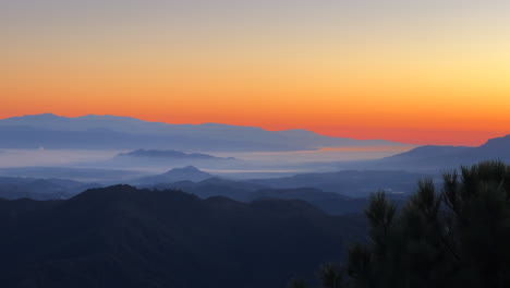 Incredible-orange-sunrise-view-from-the-top-of-a-mountain-in-Marbella-Malaga-Spain,-beautiful-sky-with-low-clouds,-4K-shot