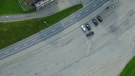 Aerial-view-of-a-car-driving-out-of-a-parking-area,-along-a-road-in-a-sleepy-town