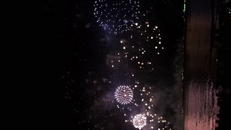 Fiesta-En-El-Mar-Resplandeciente-Hermoso-Cielo-Nocturno-Iluminado-Por-Una-Vibrante-Explosión-De-Fuegos-Artificiales