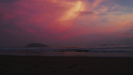 Dramatischer-Rosafarbener-Sonnenuntergang-über-Einem-Ruhigen-Strand-Und-Einer-Entfernten-Insel