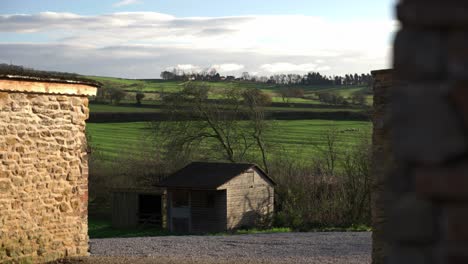Tight-peeking-view-of-fields-and-rolling-green-hills-of-North-Yorkshire-from-a-farmers-yard-on-a-cold-but-sunny-winter-day