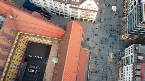 Aerial-tilt-up-shot-showing-walking-pedestrian-on-street-in-Munich-at-sunset-time,-Germany