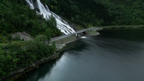 Travelling-car-drives-over-roads-in-Norway-next-to-a-waterfall