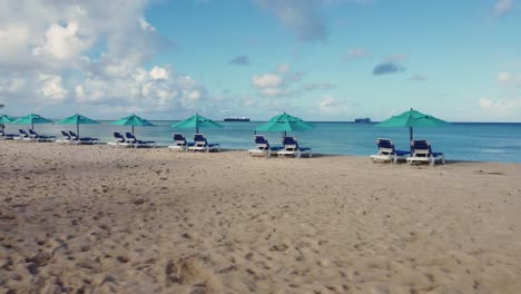 Low-angle-drone-orbit-shot-of-beach-chairs-and-umbrellas-on-a-bright-and-clear-morning