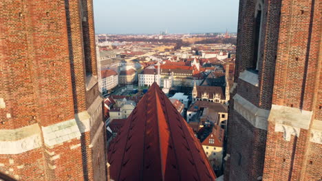Ascending-drone-shot-showing-City-of-Munich-between-two-towers-of-Frauenkirche-Church-at-sunny-day