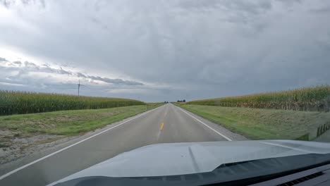 POV---driving-on-a-rural-road-past-wind-turbines-and-fields-on-a-cloudy-day-in-late-summer-in-the-Midwest