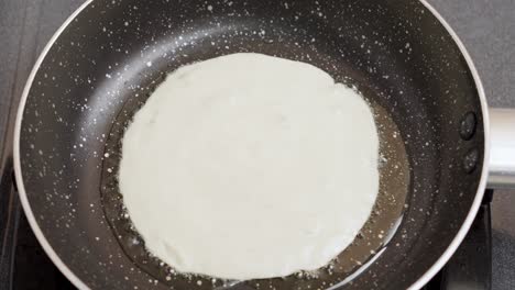 Close-up-shot-wet-pancake-batter-being-poured-into-a-metal-pan-with-Oil-Top-View