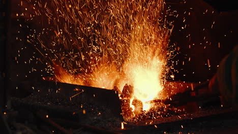 Close-up-of-a-blacksmith's-hand,-using-tongs-on-a-piece-of-metal,-stirring-up-the-fire-of-the-coal-forge