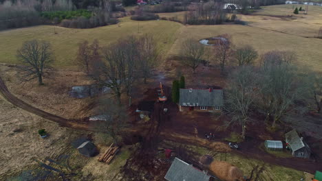 Aerial-Drone,-Rural-Country-Houses-Landscape,-Excavator-Plows-the-Soil,-Skyline