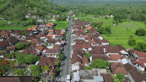 Drone-flying-over-the-main-road-of-a-small-village-panning-up-to-reveal-a-volcano-in-the-background