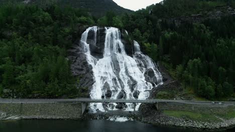 Norwegische-Straße-Vor-Einem-Wilden-Wasserfall,-Der-In-Die-Fjorde-Des-Nordmeeres-Mündet