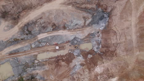 A-dynamic-drone-shot-of-a-excavator-which-empties-its-yield-into-a-mining-truck