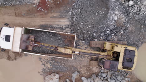 A-dynamic-drone-shot-of-a-excavator-which-empties-its-yield-into-a-mining-truck