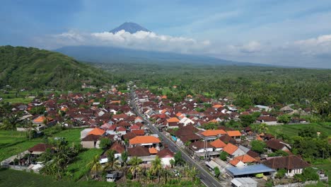 Drone-flying-over-a-small-village-with-a-volcano-in-the-background