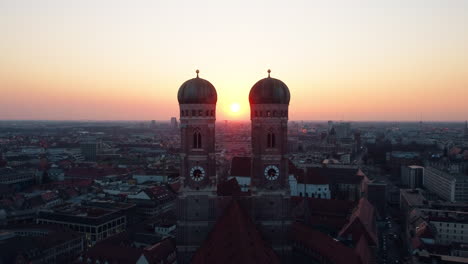 Cinematic-aerial-approach-towards-the-architectural-wonder-of-Munich-Frauenkirche,-revealing-its-awe-inspiring-grandeur-and-two-majestic-spires