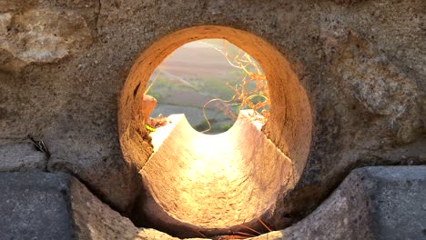 Wunderschöner-Blick-Auf-Den-Sonnenuntergang-In-Der-Goldenen-Stunde-In-Ronda-Durch-Ein-Loch-In-Einer-Wand,-Blick-Auf-Die-Natur-Und-Felder-In-Spanien,-Interessante-Perspektive,-Hoffnung-Am-Ende-Des-Tunnels,-4K-Aufnahme