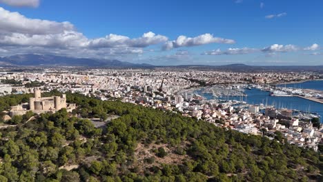 Aerial-approaching-shot-of-Castell-de-Bellver-and-Palma-City-with-harbor-in-background,-Mallorca
